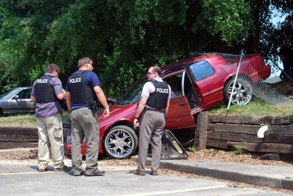 Troy Police officers stand near a car that crashed after the driver attempted to elude police.