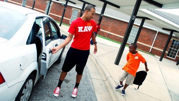 Troy University student and Kappa Alpha Psi fraternity member Chastan Thomas, 23, assists Kindergartener Jaquavin Grimes into a car as the school day ends. Grimes and fellow fraternity member Payton McGhee volunteered to help younger students into vehicles on the first day of school in order to help keep them safe.