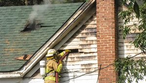  Messenger photo/Jacob Holmes A Banks volunteer firefighter works to put out a house fire off of County Road 6641. The fire began at approximately 3 p.m. Tuesday.